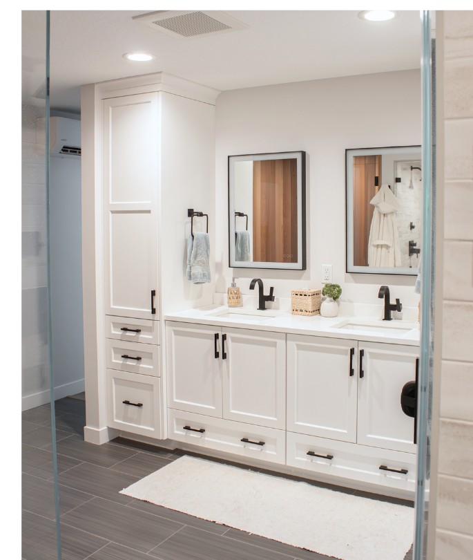 Custom white vanity with double sinks, framed mirrors, and a frameless glass shower in a primary bathroom remodel by Elias Construction