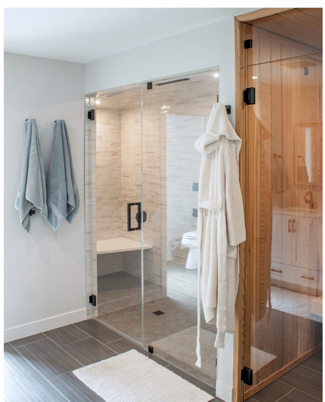Frameless glass shower and steam room with a built-in bench beside warm cedar sauna paneling by Elias Construction
