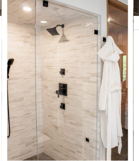 Walk-in steam shower with rainfall head, body sprays, and a hand shower behind frameless glass
